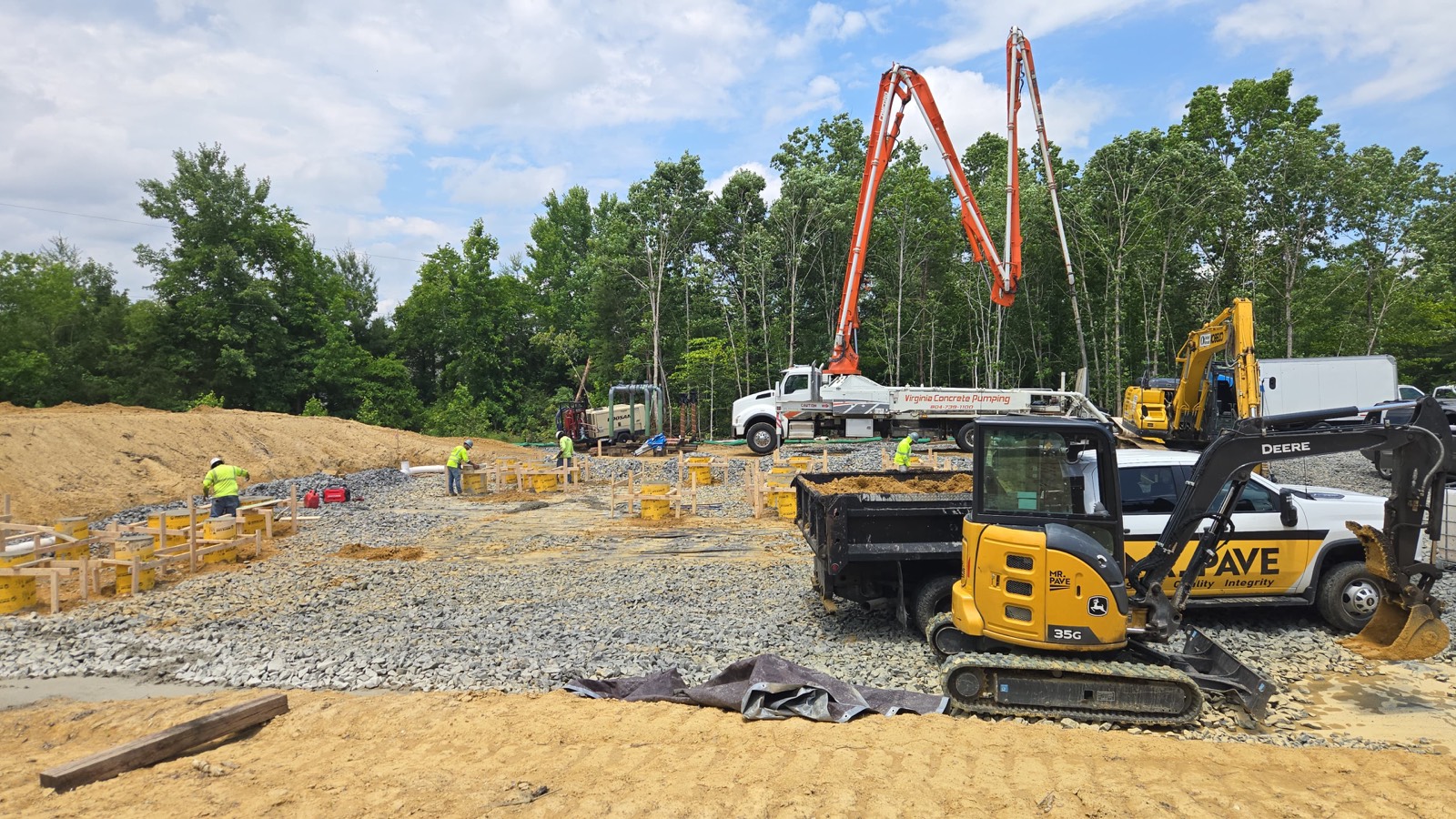 Excavator and dump truck positioned beside footing forms on an active Oxen Civil construction site