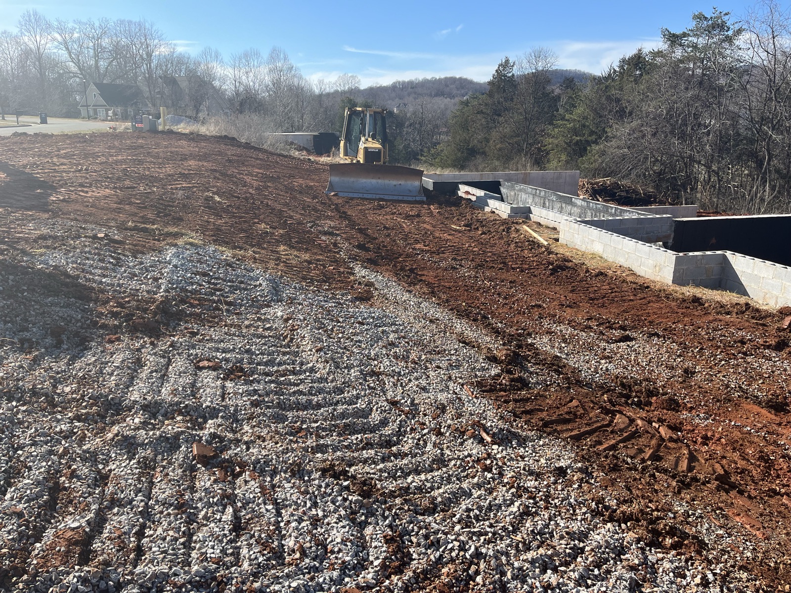 Gravel foundation base laid out inside footing forms on a hillside site