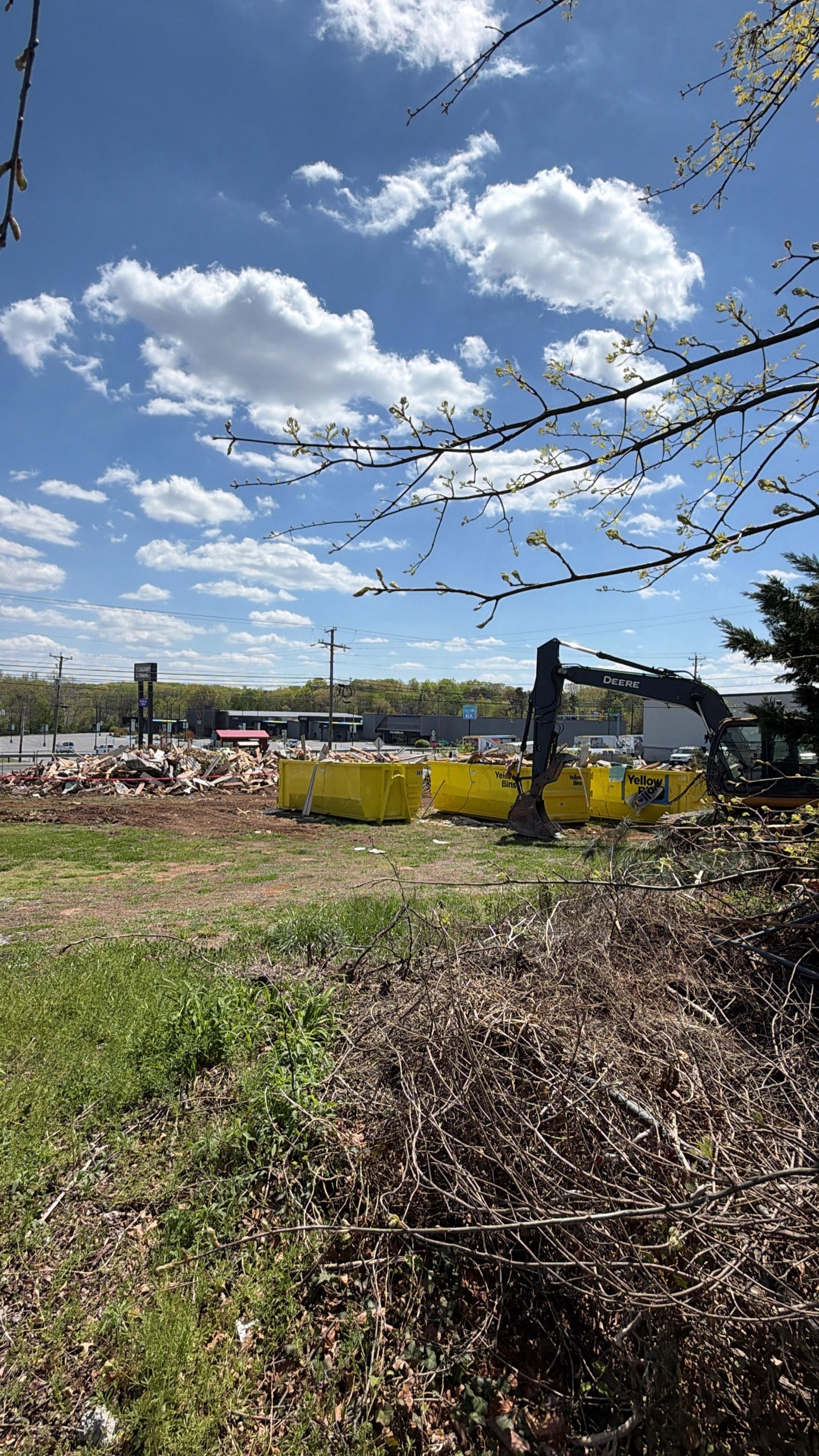 Yellow roll-off dumpster bins loaded with demolition debris on a job site