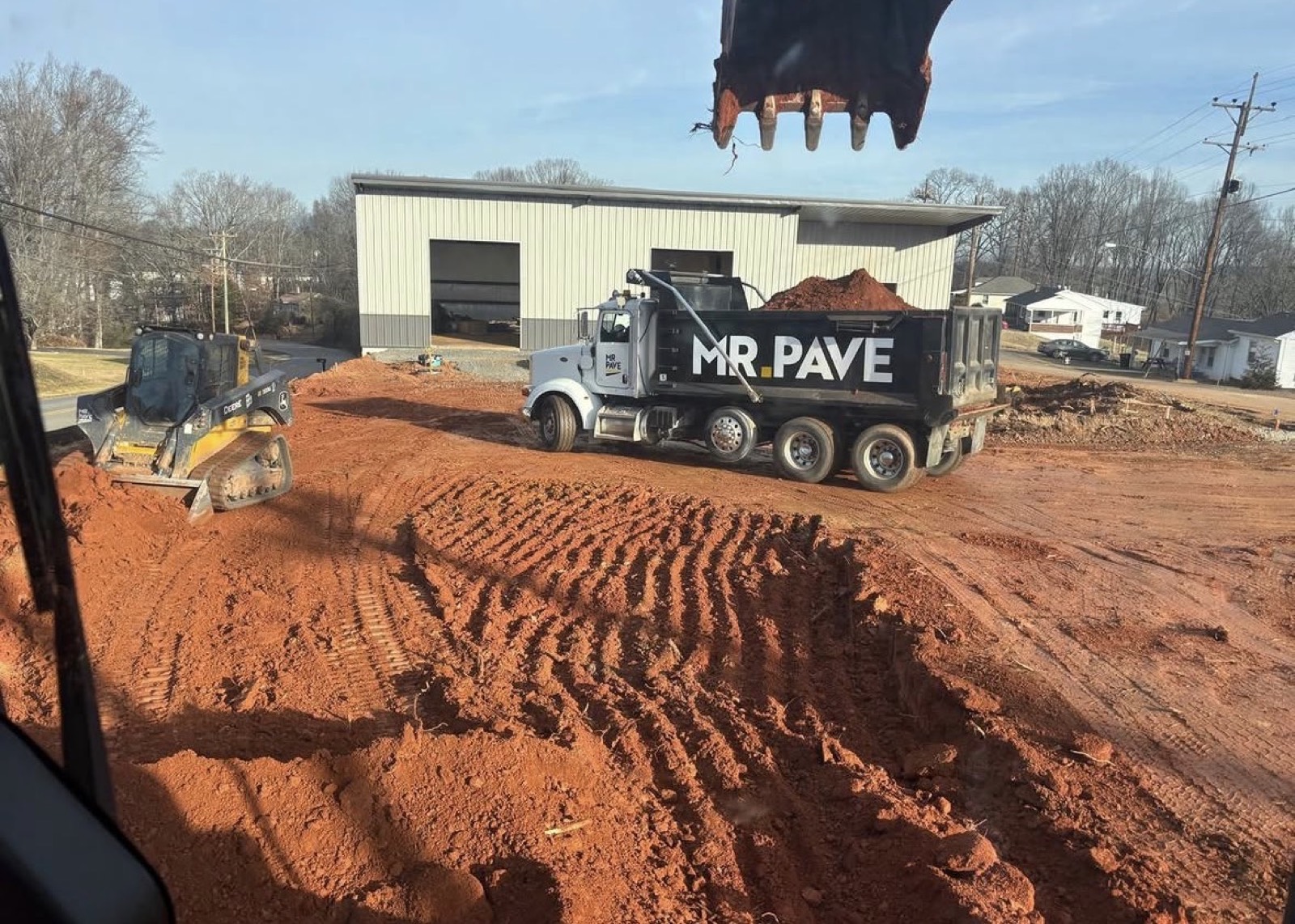 Mr. Pave branded dump truck being loaded by an excavator on an active Oxen Civil jobsite