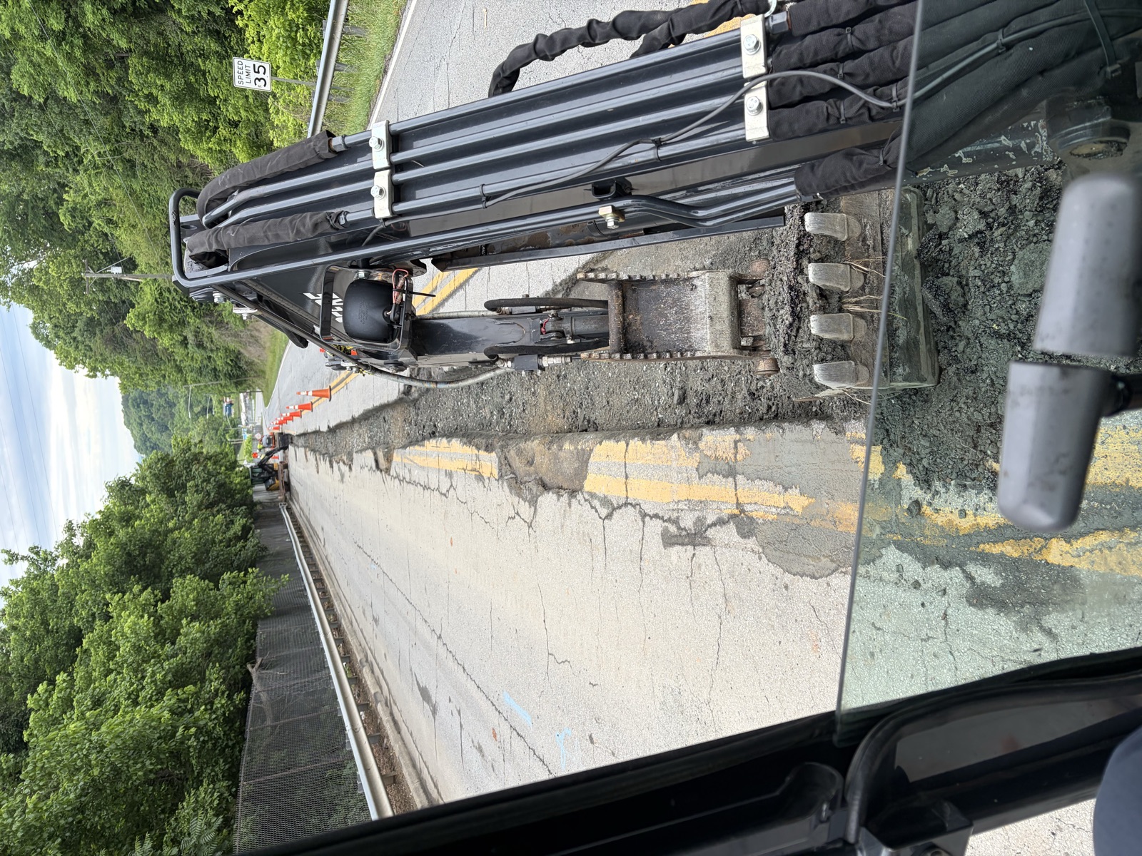 Excavator digging a utility trench along the shoulder of a highway