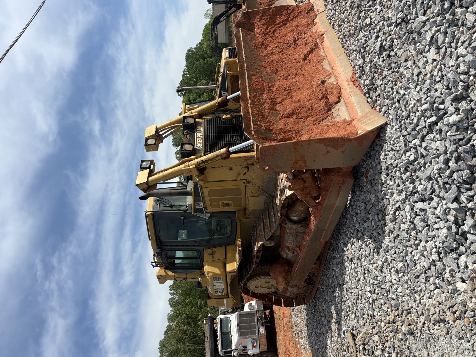 CAT loader placing graded soil next to a gravel base course on an active site