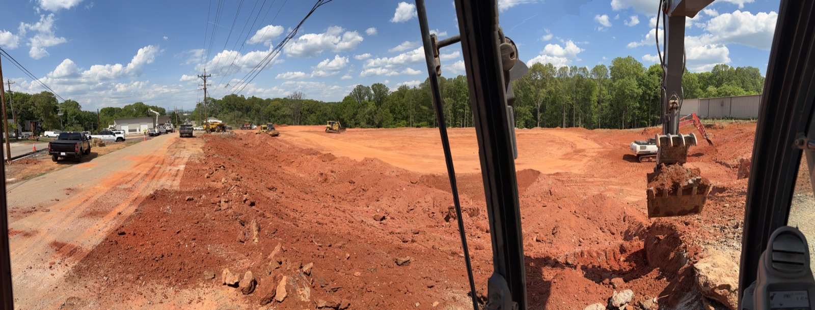 Excavator, dozer, and haul truck staged on an active red-clay grading site