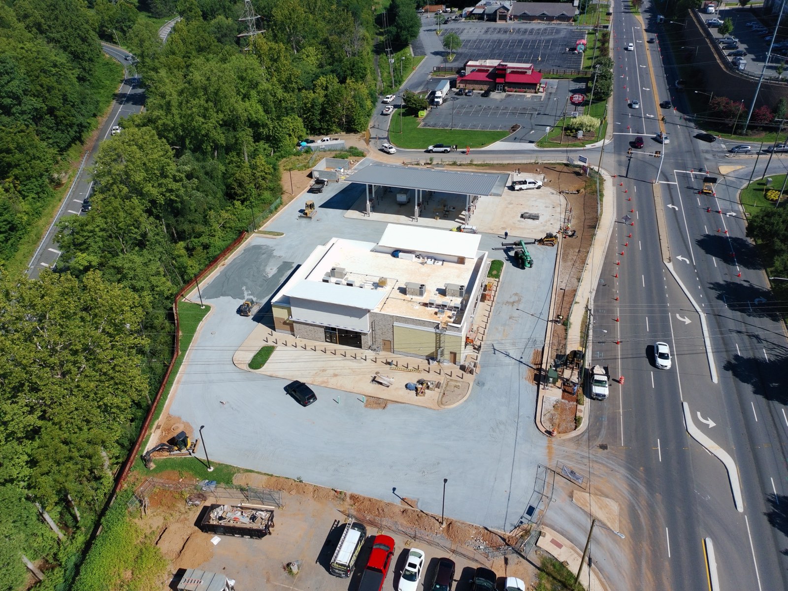 Aerial view of a finished commercial parking lot, fuel canopy, and new asphalt approach off the highway